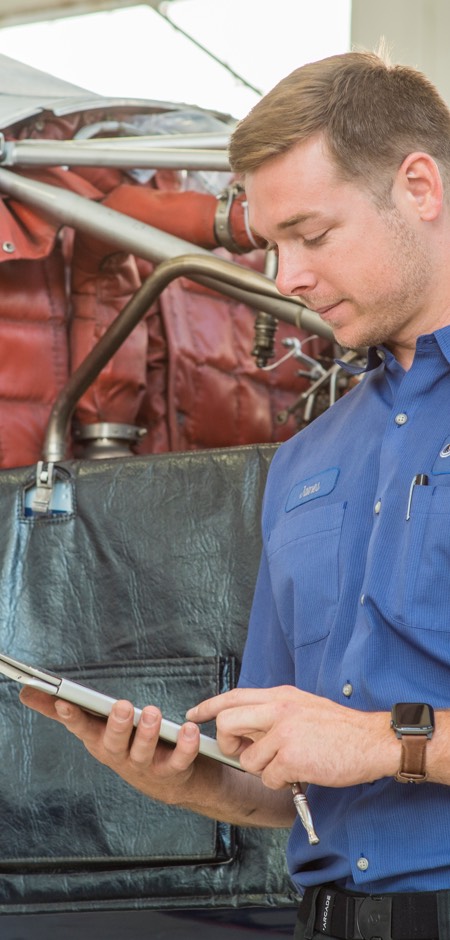 A man in a mechanical workshop reviewing content on a tablet.